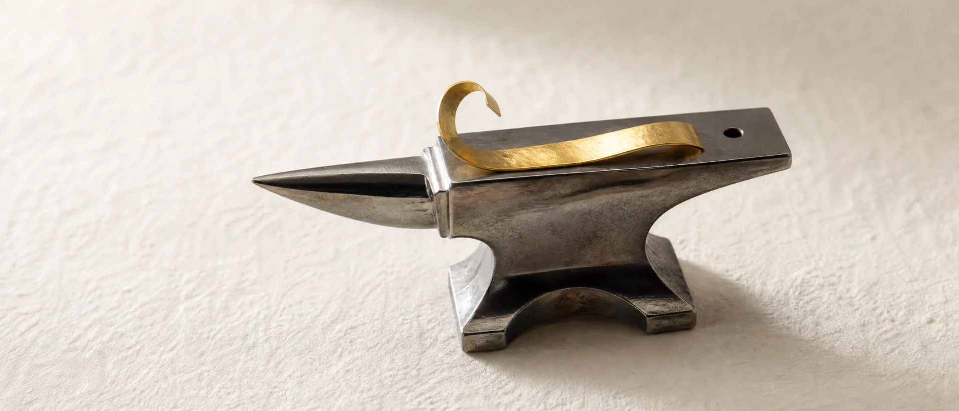 Gold ribbon shaped over an anvil during the refining process